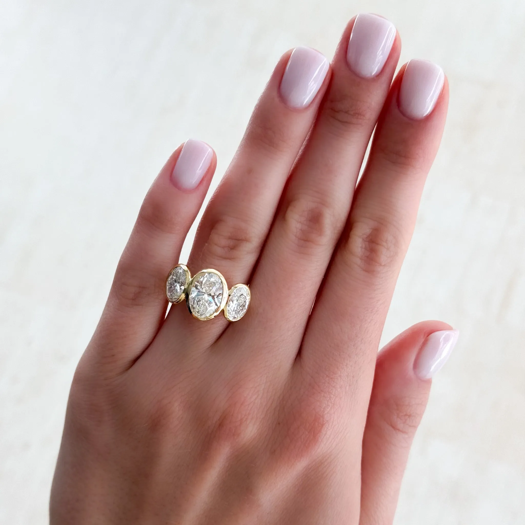 Penumbra Bezel Triad Engagement Ring With Oval Cut Diamonds