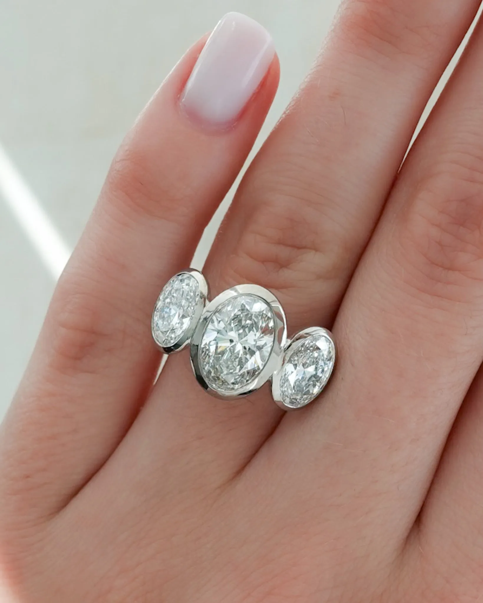 Penumbra Bezel Triad Engagement Ring With Oval Cut Diamonds